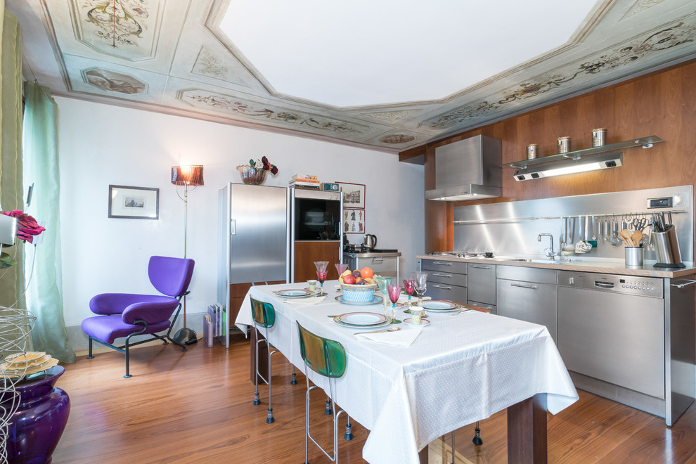 Stilmix Wohnküche ohne Insel in L-Form mit flächenbündigen Schrankfronten, Edelstahlfronten, Küchenrückwand in Metallic, Küchengeräten aus Edelstahl, braunem Holzboden und braunem Boden in Venedig