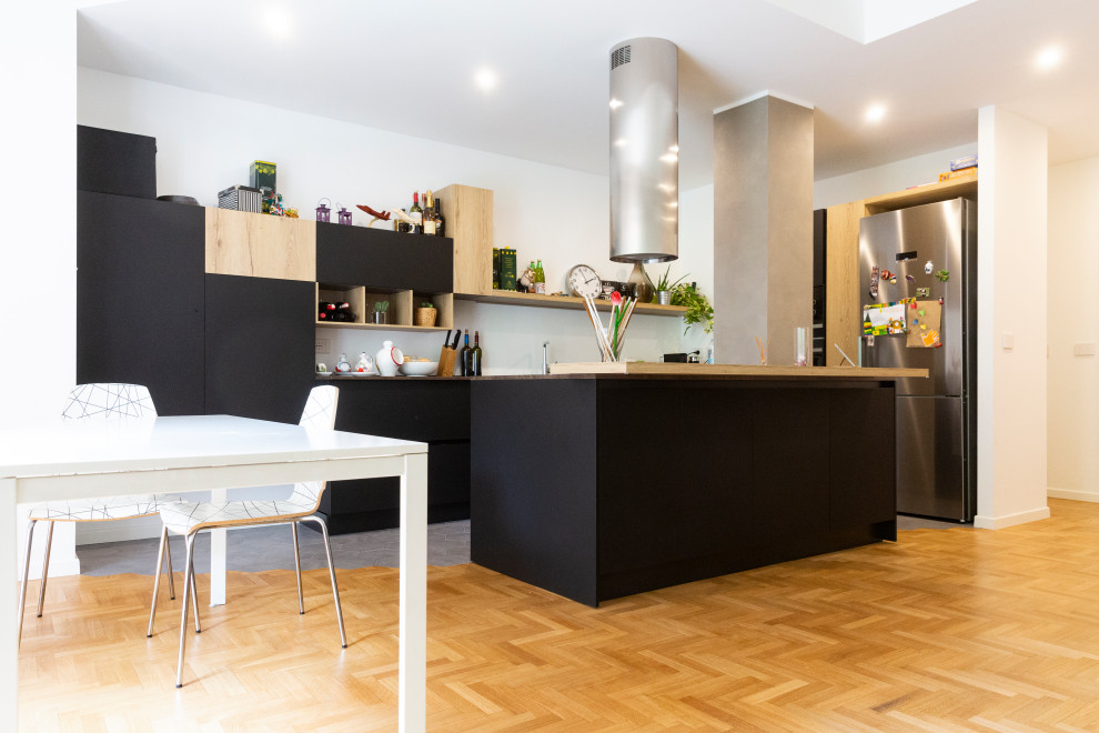 Immagine di una cucina minimalista con ante nere e parquet chiaro