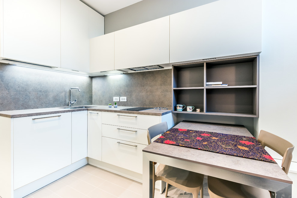 Kleine Moderne Wohnküche in U-Form mit flächenbündigen Schrankfronten, weißen Schränken, Küchenrückwand in Grau, Halbinsel und beigem Boden in Mailand