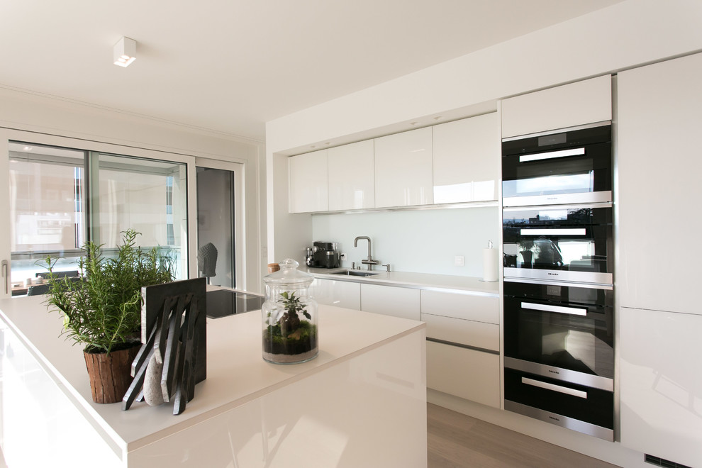Ejemplo de cocina lineal moderna de tamaño medio abierta con armarios con paneles lisos, puertas de armario blancas y una isla