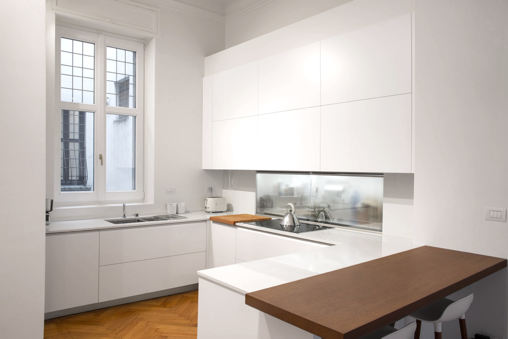 Large contemporary u-shaped kitchen/diner in Milan with a double-bowl sink, flat-panel cabinets, white cabinets, quartz worktops, white splashback, marble splashback, stainless steel appliances, medium hardwood flooring and a breakfast bar.