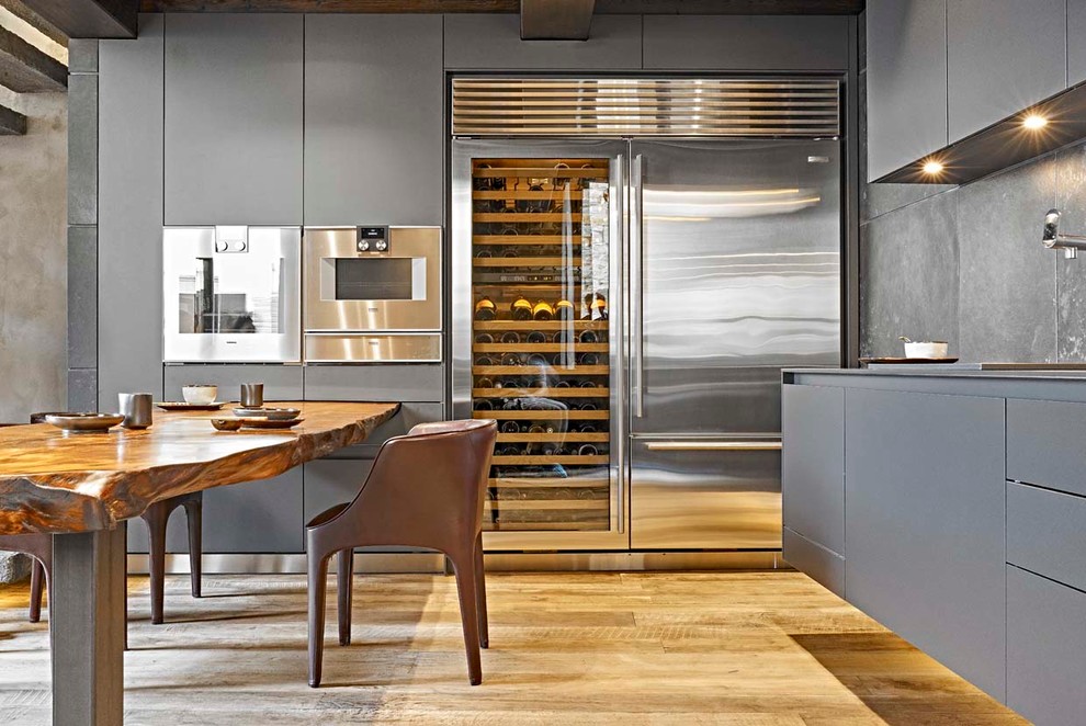Exempel på ett modernt kök, med släta luckor, grå skåp, grått stänkskydd, rostfria vitvaror och ljust trägolv