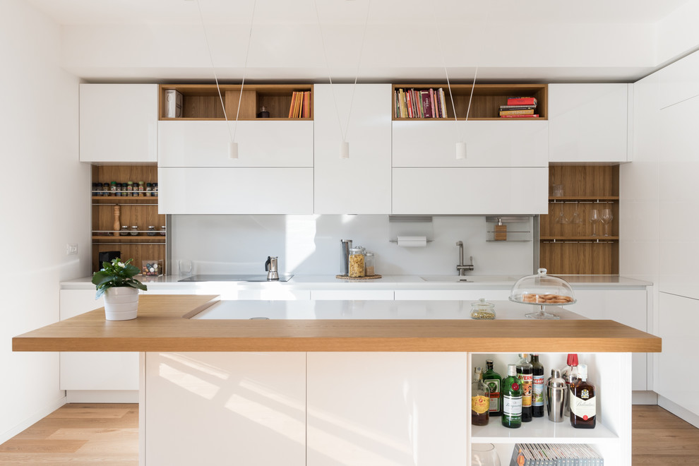 Inspiration for a scandinavian kitchen in Rome with flat-panel cabinets, white cabinets, white splashback, light hardwood flooring, an island, a single-bowl sink, beige floors and white worktops.