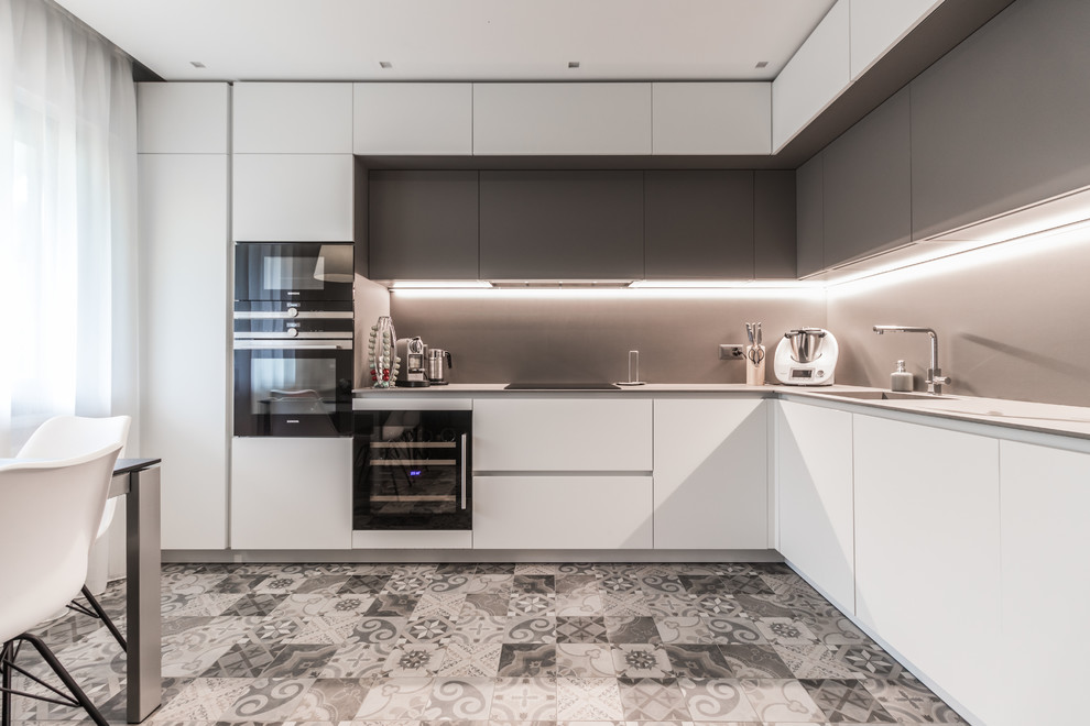 Large contemporary l-shaped kitchen/diner in Other with flat-panel cabinets, white cabinets, grey splashback, stainless steel appliances, ceramic flooring, no island, grey worktops and grey floors.