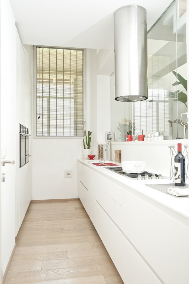 Geschlossene, Zweizeilige Moderne Küche mit flächenbündigen Schrankfronten, weißen Schränken, Küchenrückwand in Weiß und hellem Holzboden in Mailand