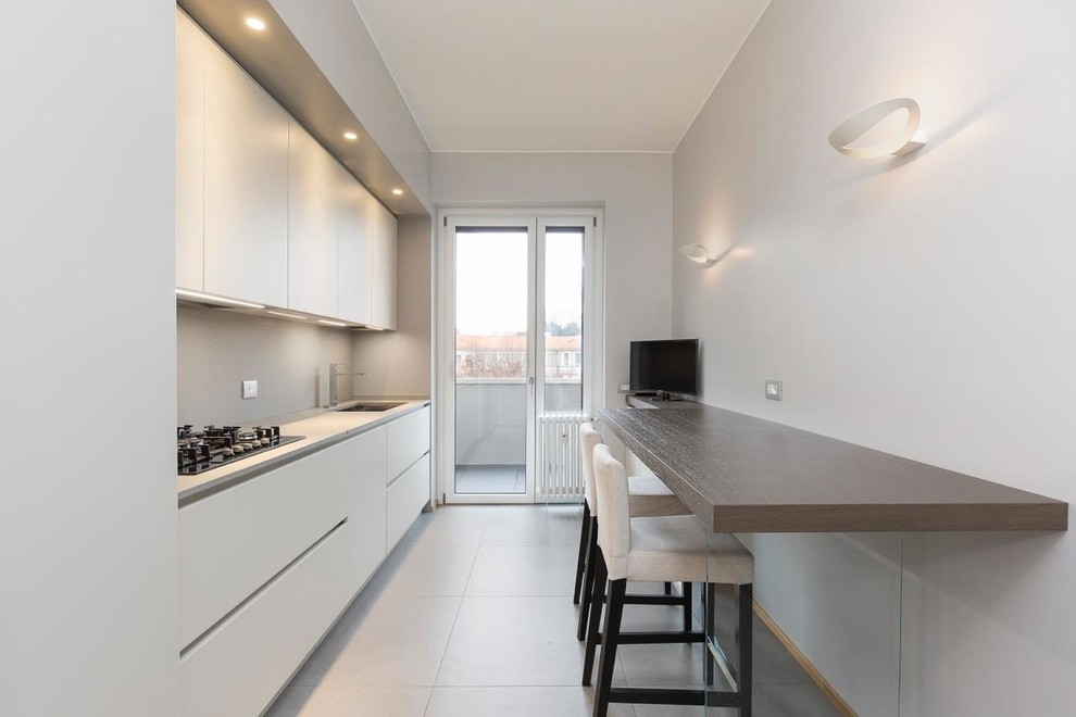 Example of a trendy single-wall gray floor enclosed kitchen design in Milan with flat-panel cabinets, white cabinets, an undermount sink, gray backsplash and gray countertops