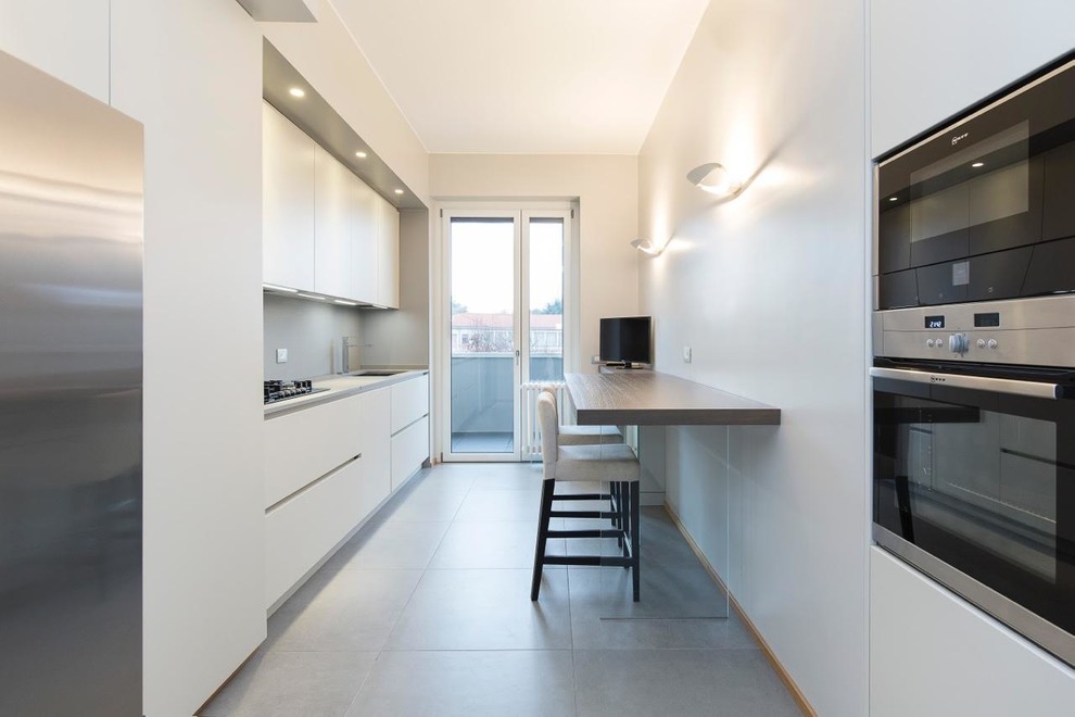 Immagine di una cucina lineare design chiusa con ante lisce, ante bianche, paraspruzzi grigio e top grigio