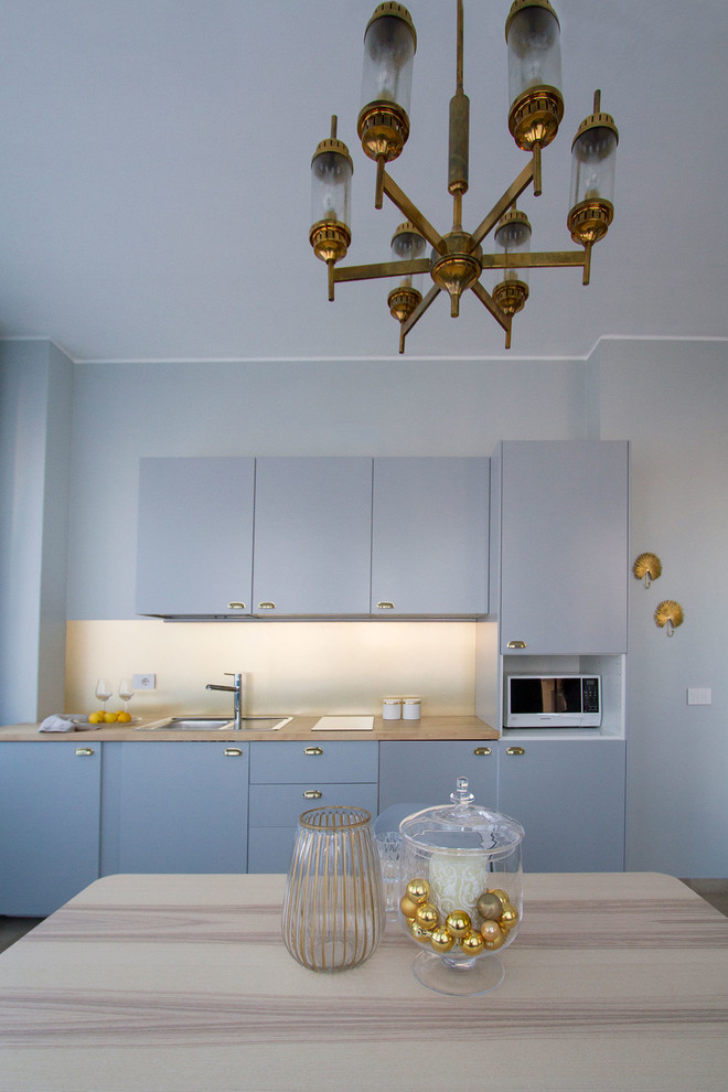 На фото: кухня в современном стиле с синими фасадами, деревянной столешницей и бежевой столешницей с