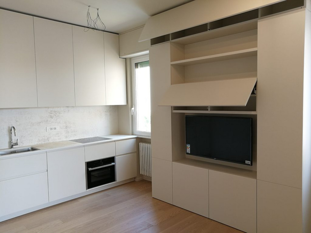 Photo of a small contemporary single-wall open plan kitchen in Milan with a submerged sink, flat-panel cabinets, beige cabinets, engineered stone countertops, light hardwood flooring and beige worktops.