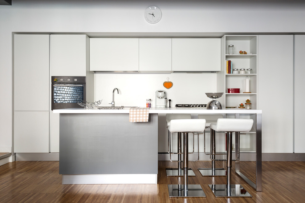 Immagine di una cucina moderna di medie dimensioni con ante lisce, ante bianche, paraspruzzi bianco, pavimento in legno massello medio, pavimento marrone e lavello sottopiano