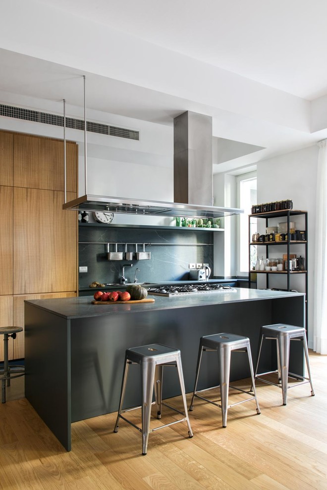 Zweizeilige Industrial Küche mit flächenbündigen Schrankfronten, braunen Schränken, Küchenrückwand in Grau, braunem Holzboden, Kücheninsel, braunem Boden und grauer Arbeitsplatte in Mailand