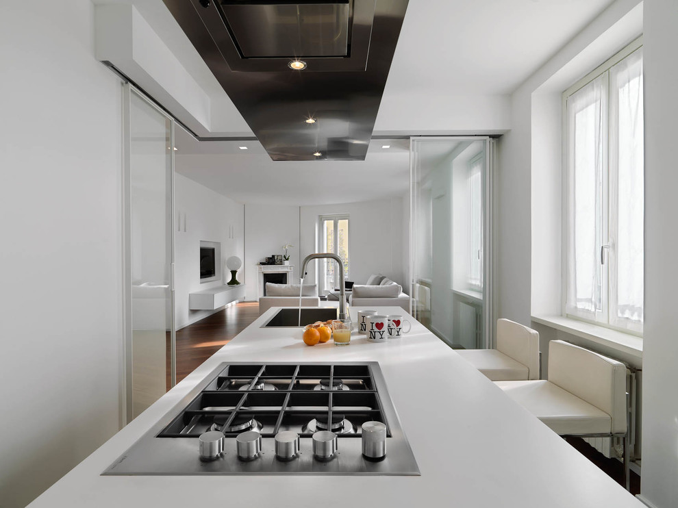 Immagine di una cucina minimal chiusa e di medie dimensioni con ante lisce, ante bianche, top in quarzo composito, elettrodomestici in acciaio inossidabile, parquet scuro e pavimento marrone