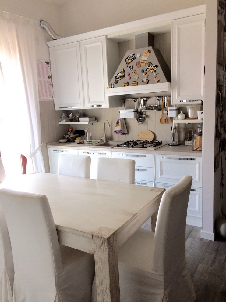 Einzeilige Shabby-Style Küche mit weißen Schränken, Laminat-Arbeitsplatte, Küchenrückwand in Beige, Rückwand aus Keramikfliesen, bunten Elektrogeräten, gebeiztem Holzboden, braunem Boden und beiger Arbeitsplatte in Mailand