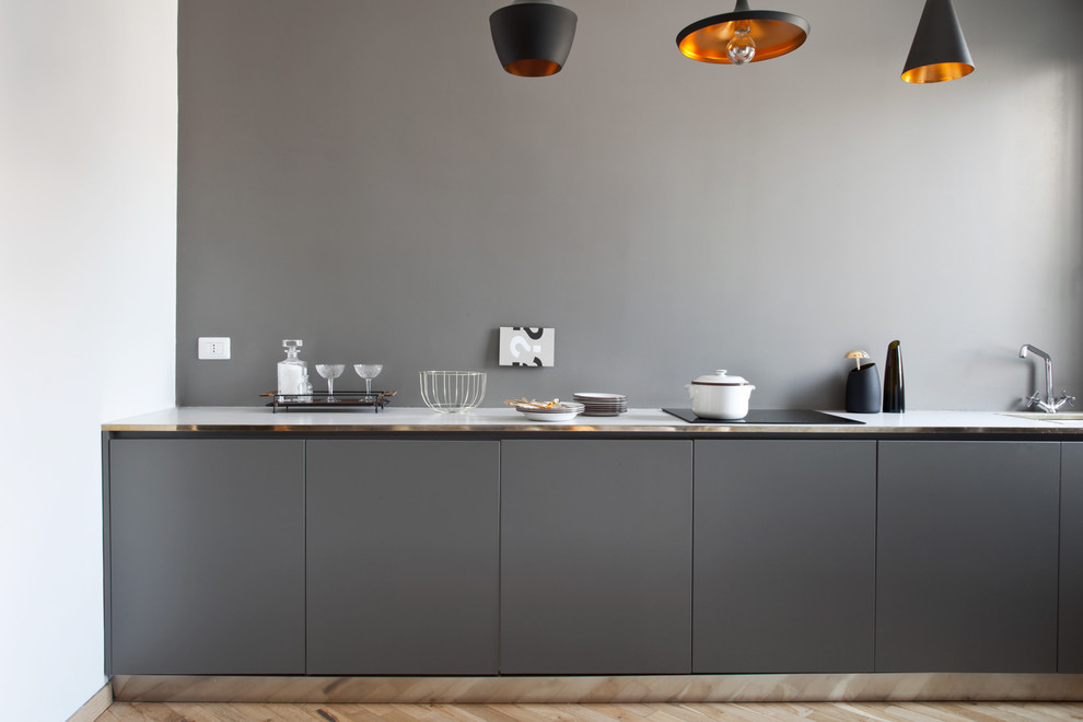 Ejemplo de cocina minimalista con armarios con paneles lisos, puertas de armario grises y salpicadero verde
