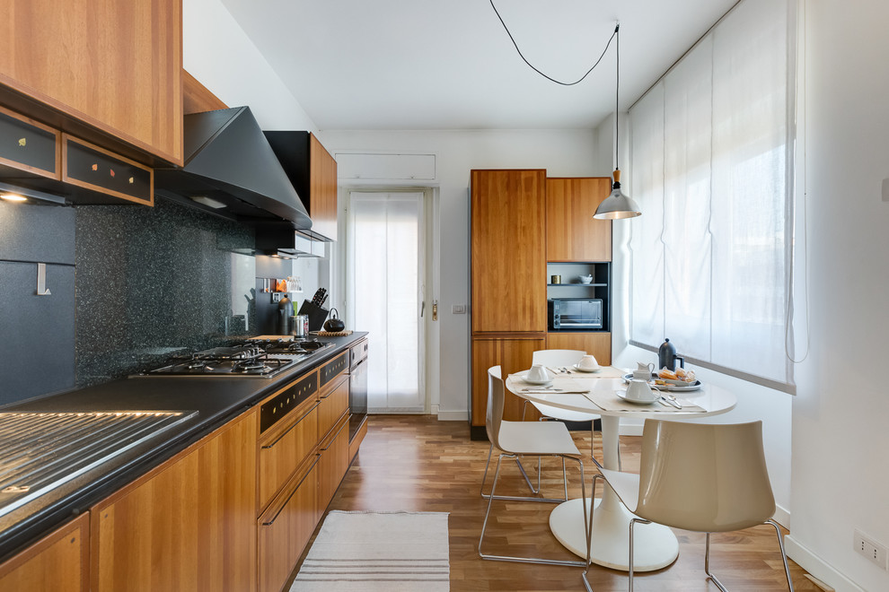 Cette photo montre une cuisine américaine linéaire moderne en bois brun avec un placard à porte plane, une crédence noire, un sol en bois brun, un évier posé et une crédence en dalle de pierre.