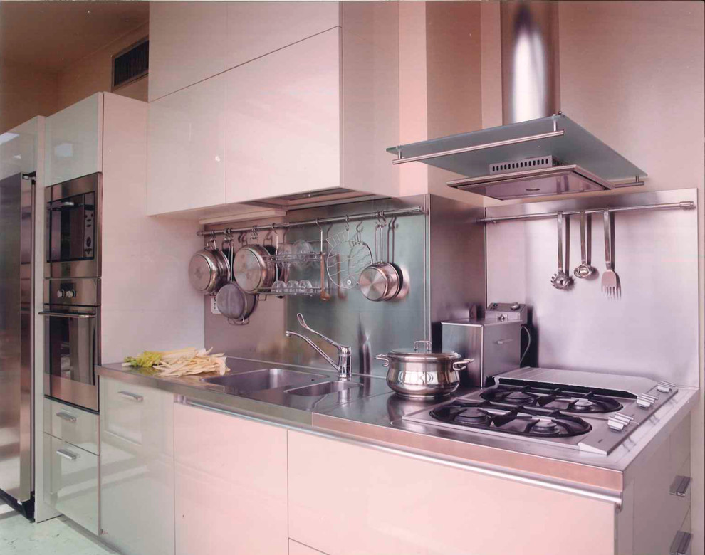 Immagine di una cucina moderna di medie dimensioni con lavello a doppia vasca, ante lisce, ante bianche, top in laminato, paraspruzzi a effetto metallico, elettrodomestici in acciaio inossidabile, pavimento in marmo e nessuna isola
