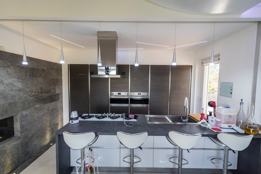 Immagine di una grande cucina moderna con lavello a doppia vasca, ante a filo, ante grigie, top in laminato, elettrodomestici in acciaio inossidabile, pavimento in gres porcellanato, pavimento bianco e top grigio