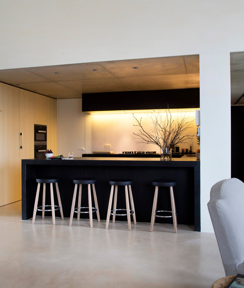 Cette photo montre une cuisine parallèle éclectique avec un placard à porte plane, sol en béton ciré, une péninsule et un sol blanc.
