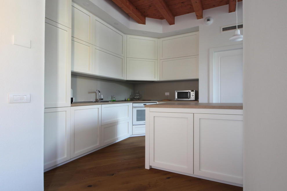 Inredning av ett lantligt stort brun brunt kök, med en nedsänkt diskho, luckor med infälld panel, vita skåp, träbänkskiva, grått stänkskydd, stänkskydd i skiffer, vita vitvaror, mellanmörkt trägolv, en köksö och brunt golv