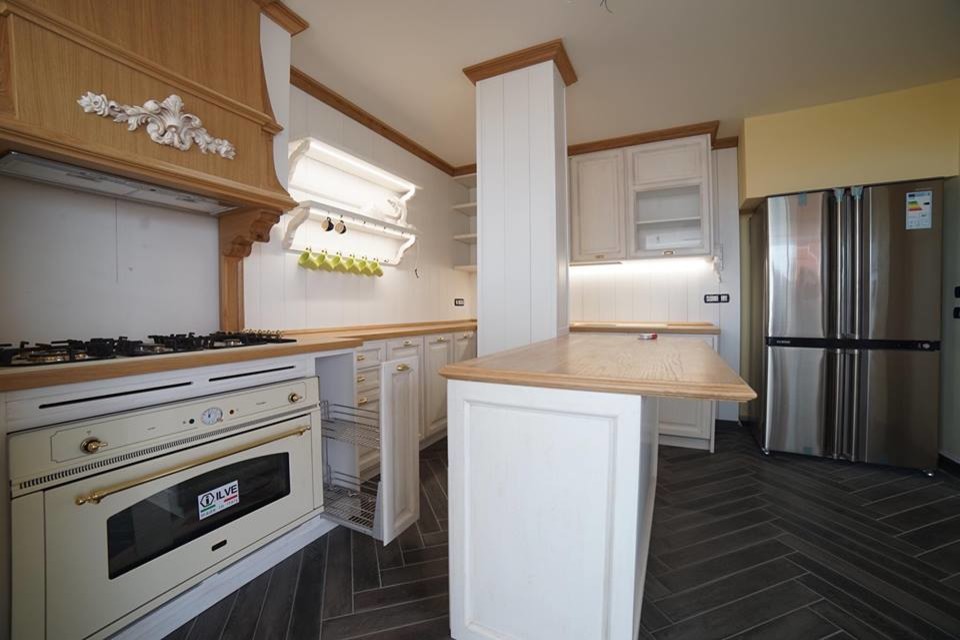 Imagen de cocinas en L romántica de tamaño medio abierta con armarios con paneles con relieve, puertas de armario blancas y encimera de madera