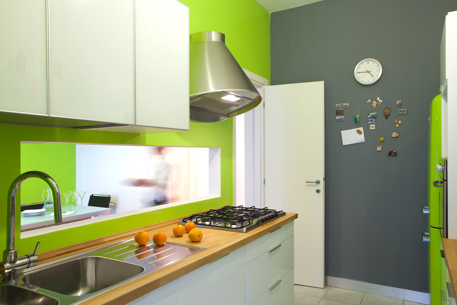 Example of a small trendy u-shaped enclosed kitchen design in Milan with a drop-in sink, glass-front cabinets, white cabinets, wood countertops, green backsplash and paneled appliances