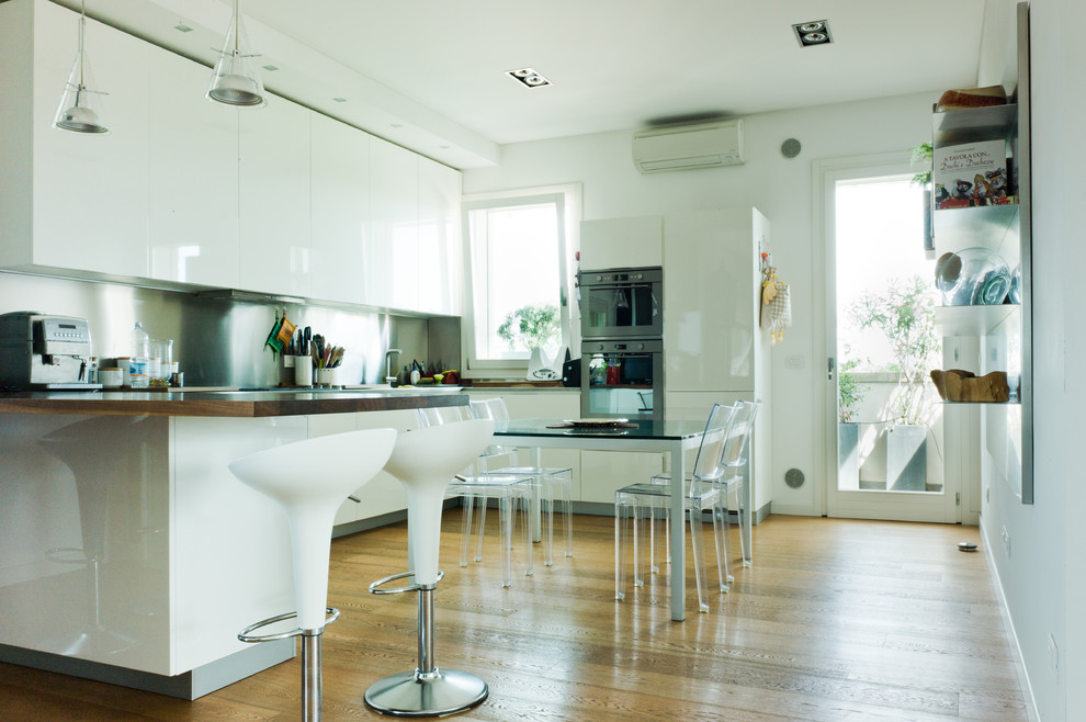 Immagine di una grande cucina contemporanea con ante lisce, ante bianche, paraspruzzi a effetto metallico, elettrodomestici in acciaio inossidabile e parquet chiaro