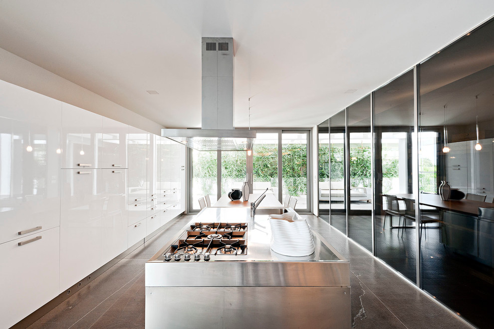 Inredning av ett modernt mycket stort kök och matrum, med en integrerad diskho, vita skåp, bänkskiva i rostfritt stål, en köksö och släta luckor