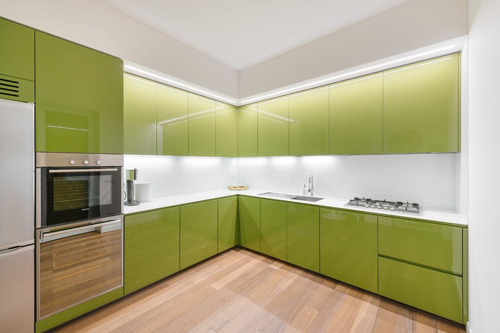 ミラノにある広いコンテンポラリースタイルのおしゃれなL型キッチン (フラットパネル扉のキャビネット、緑のキャビネット、白いキッチンパネル、無垢フローリング) の写真