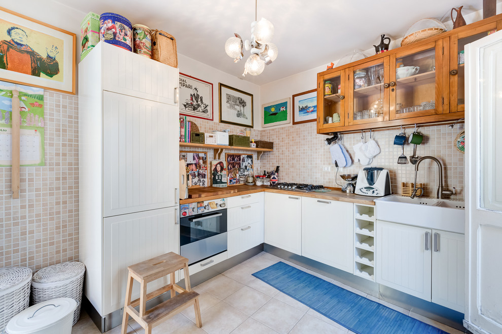 Modelo de cocinas en L bohemia de tamaño medio con fregadero sobremueble, puertas de armario blancas, salpicadero beige y electrodomésticos con paneles