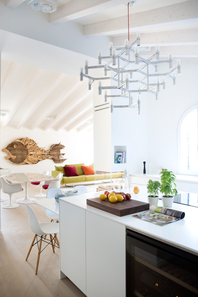 Mittelgroße Moderne Küche mit flächenbündigen Schrankfronten, weißen Schränken, hellem Holzboden und Kücheninsel in Sonstige