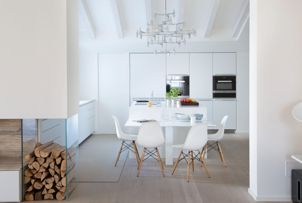 Moderne Wohnküche mit flächenbündigen Schrankfronten, weißen Schränken, schwarzen Elektrogeräten, hellem Holzboden und Kücheninsel in Sonstige