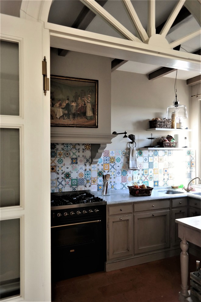 Cette image montre une cuisine ouverte rustique en U de taille moyenne avec un évier encastré, un placard à porte affleurante, plan de travail en marbre, une crédence en céramique, un électroménager noir et tomettes au sol.