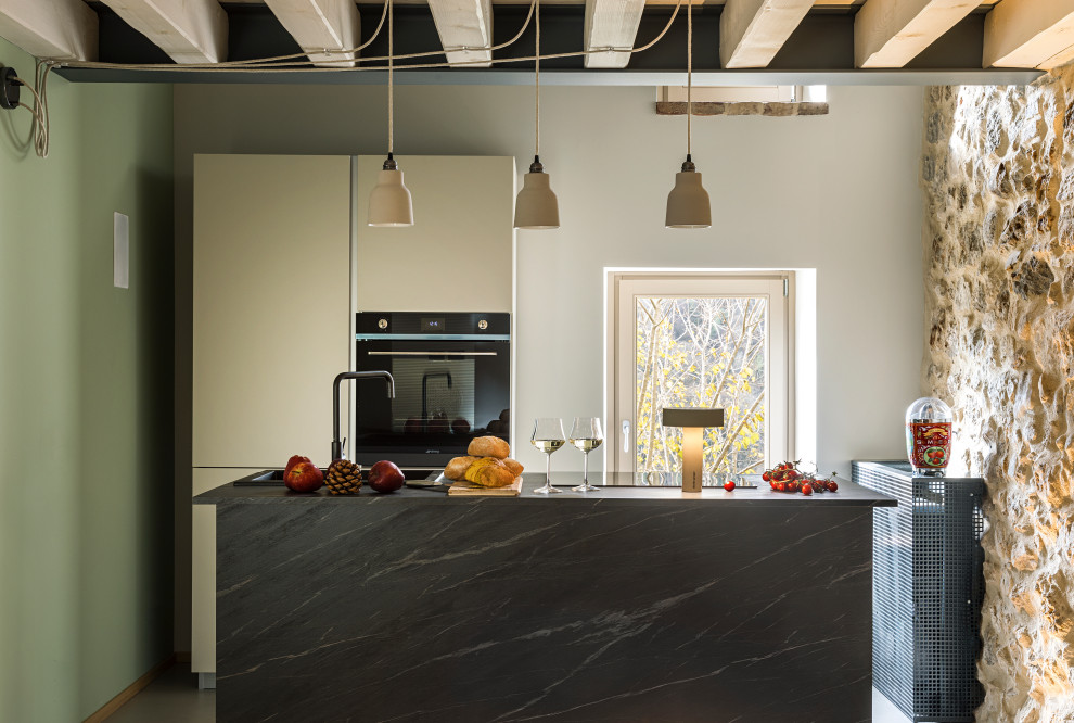 Zweizeilige, Mittelgroße Rustikale Küche mit Einbauwaschbecken, flächenbündigen Schrankfronten, weißen Schränken, schwarzen Elektrogeräten, Kücheninsel und grauer Arbeitsplatte in Mailand
