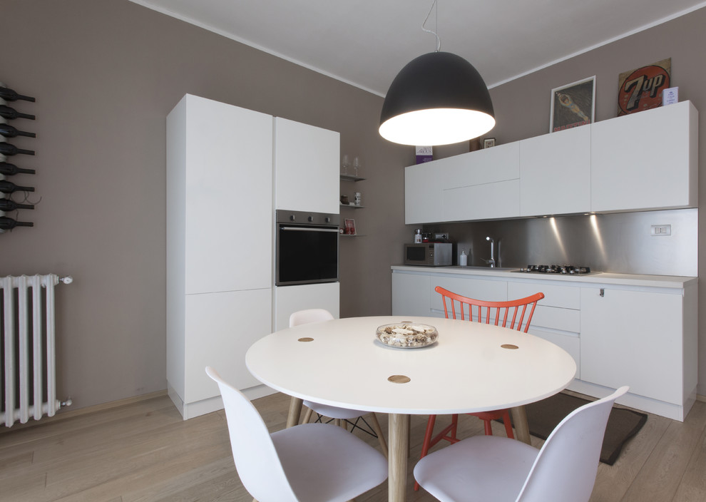 Bild på ett mellanstort funkis linjärt kök med öppen planlösning, med en enkel diskho, släta luckor, vita skåp, laminatbänkskiva, stänkskydd med metallisk yta, rostfria vitvaror och mellanmörkt trägolv