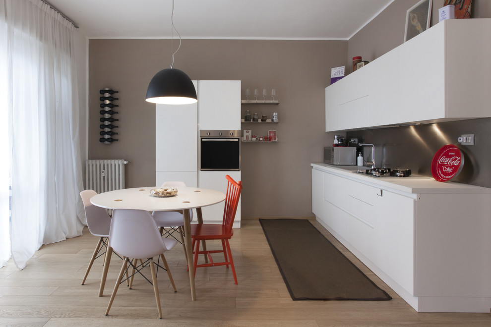 Exempel på ett mellanstort modernt linjärt kök och matrum, med en enkel diskho, släta luckor, vita skåp, laminatbänkskiva, stänkskydd med metallisk yta, rostfria vitvaror och mellanmörkt trägolv