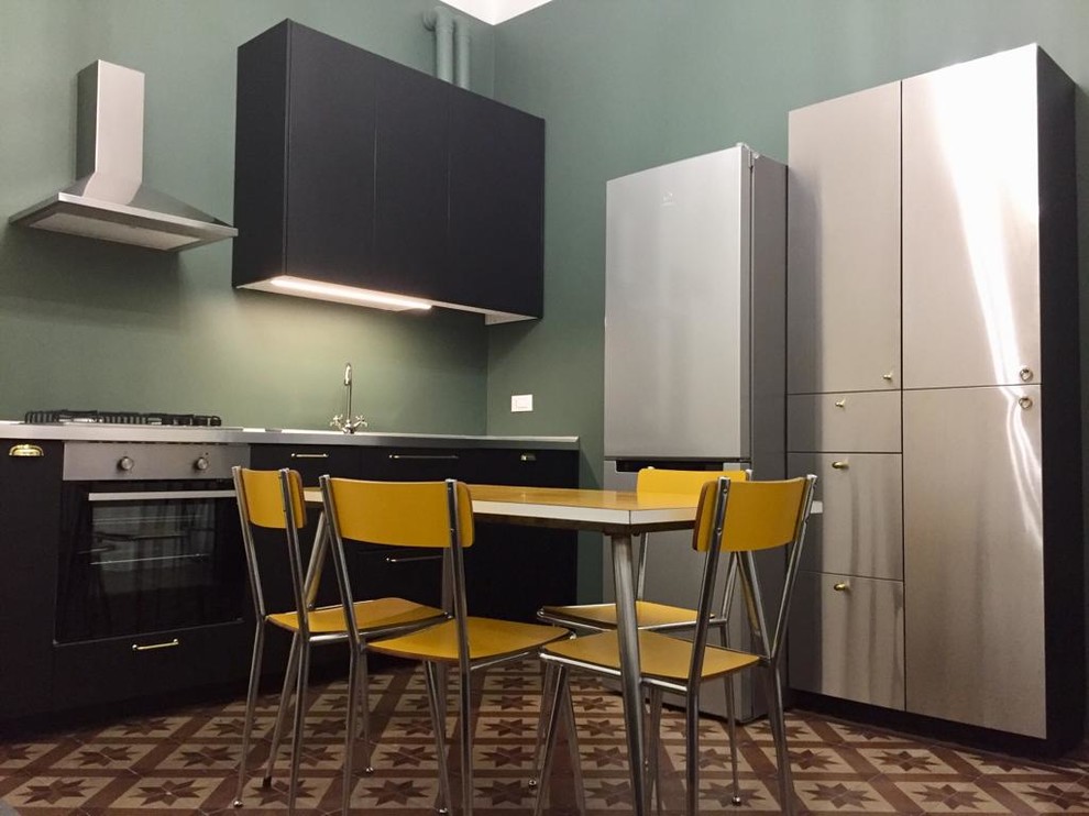 Photo of a small midcentury l-shaped open plan kitchen in Milan with a built-in sink, stainless steel cabinets, stainless steel worktops, stainless steel appliances and cement flooring.