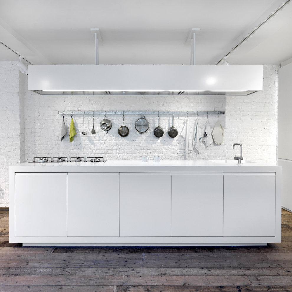 Imagen de cocina urbana abierta con armarios con paneles lisos, puertas de armario blancas, salpicadero blanco, suelo de madera clara y una isla