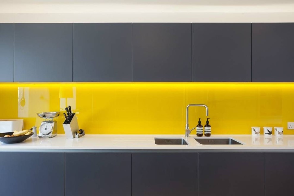 Пример оригинального дизайна: п-образная кухня среднего размера в стиле модернизм с обеденным столом, врезной мойкой, фасадами с декоративным кантом, черными фасадами, столешницей из кварцевого агломерата, желтым фартуком, цветной техникой, полуостровом и черной столешницей