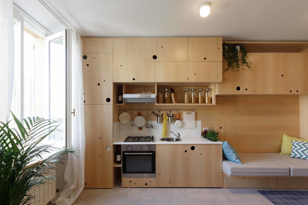 Cette image montre une petite cuisine ouverte linéaire design en bois brun avec un évier encastré, un placard à porte plane, une crédence blanche, un électroménager en acier inoxydable et aucun îlot.