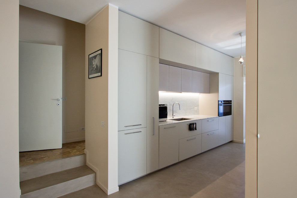 Idéer för ett stort modernt vit kök, med en undermonterad diskho, släta luckor, grå skåp, marmorbänkskiva, vitt stänkskydd, stänkskydd i marmor, svarta vitvaror, betonggolv, en köksö och grått golv
