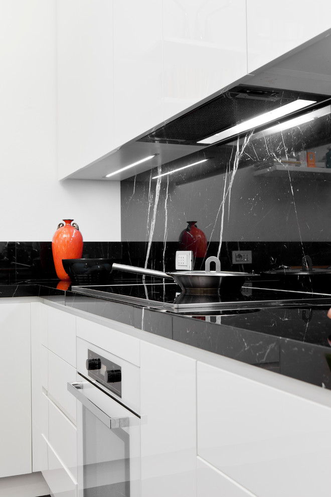 Design ideas for a large contemporary kitchen in Milan with an integrated sink, flat-panel cabinets, white cabinets, marble worktops, black splashback, stone slab splashback, white appliances and marble flooring.