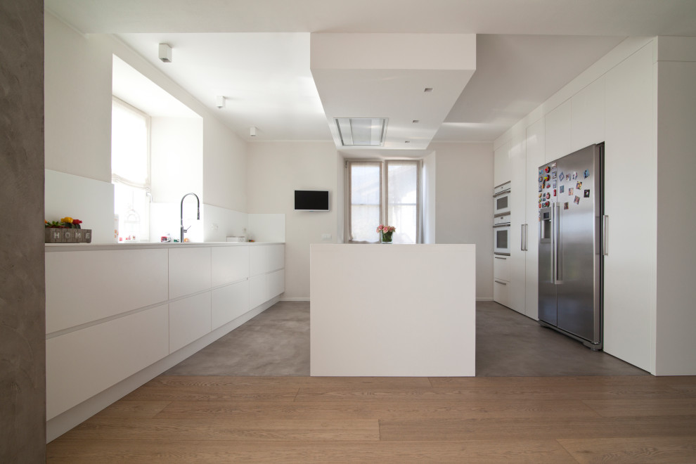 This is an example of a medium sized modern single-wall kitchen/diner in Other with an integrated sink, flat-panel cabinets, white cabinets, composite countertops, stainless steel appliances, an island and white worktops.