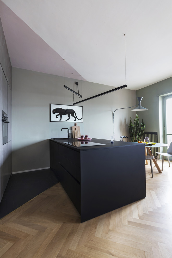 Esempio di un cucina con isola centrale design con ante a filo, ante nere, elettrodomestici in acciaio inossidabile e top nero