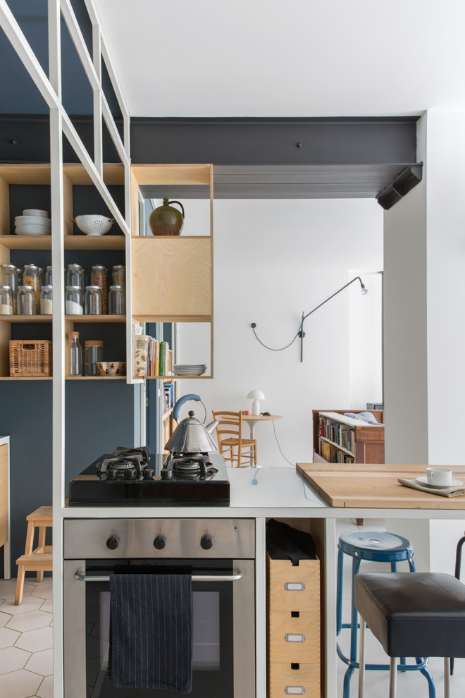 Cette image montre une cuisine ouverte linéaire urbaine en bois clair avec un placard sans porte, un électroménager noir, un sol blanc et un plan de travail blanc.