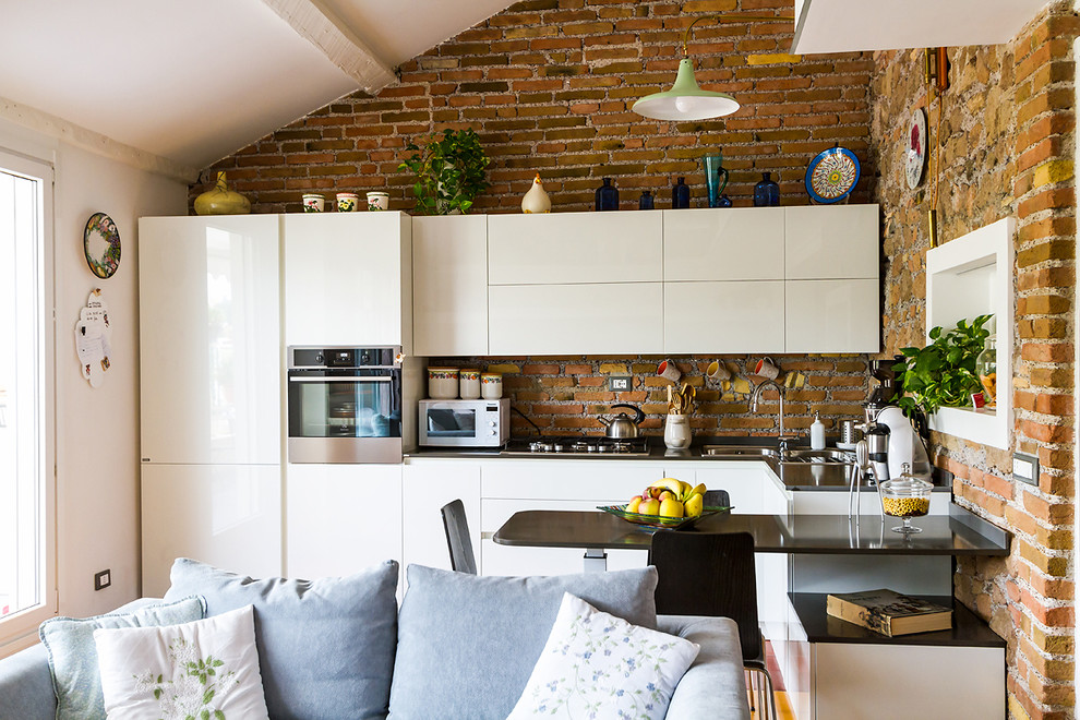 Immagine di una cucina minimal di medie dimensioni con ante bianche, top in quarzo composito, paraspruzzi in mattoni, parquet chiaro, penisola e top grigio