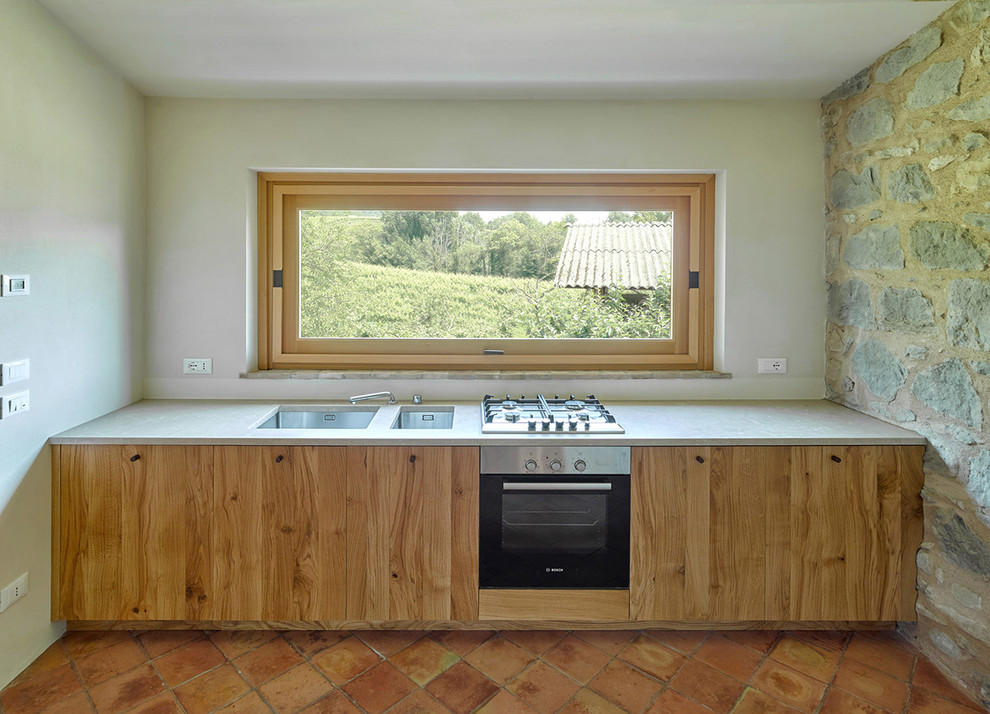Exempel på ett mellanstort rustikt linjärt kök, med en undermonterad diskho, släta luckor, skåp i ljust trä, bänkskiva i betong, rostfria vitvaror och klinkergolv i terrakotta