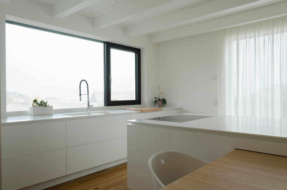 Exempel på ett mellanstort skandinaviskt vit vitt kök, med en integrerad diskho, släta luckor, vita skåp, bänkskiva i koppar, svarta vitvaror, ljust trägolv och en köksö