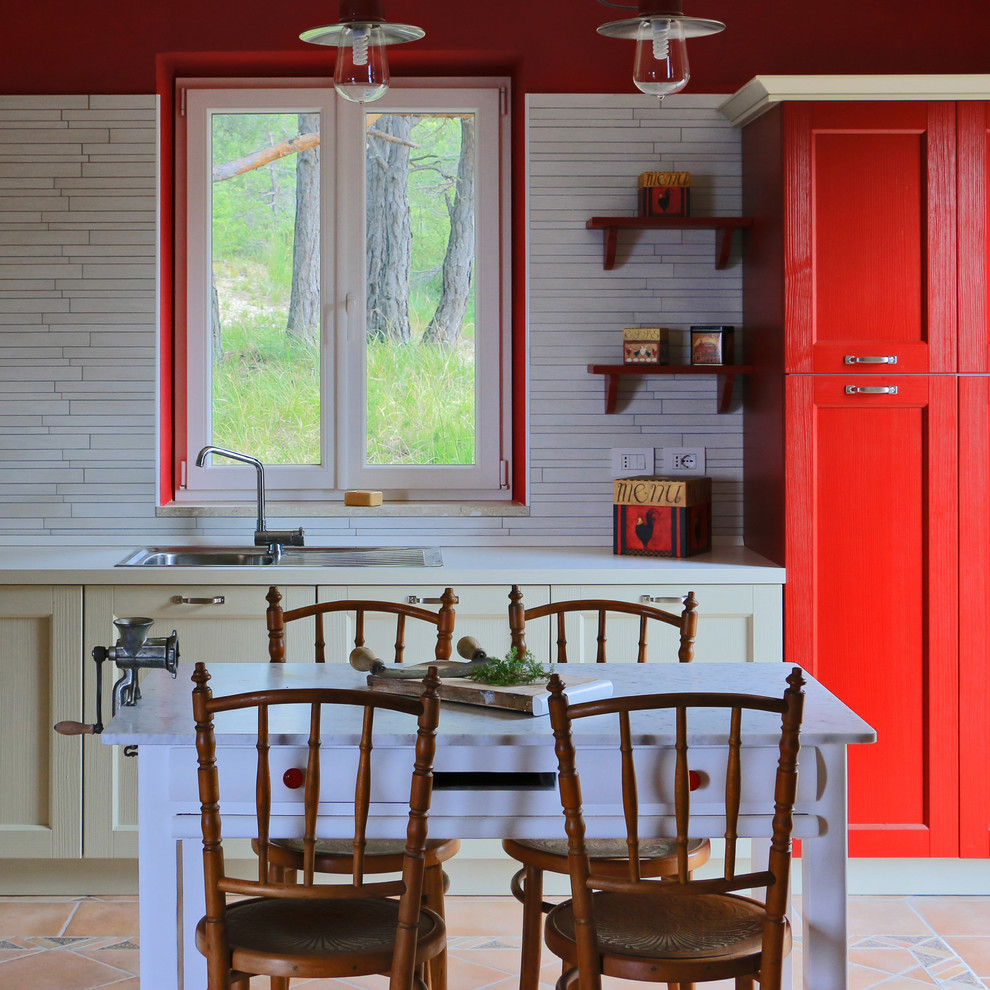 Пример оригинального дизайна: прямая кухня в стиле кантри с обеденным столом, фасадами с утопленной филенкой, красными фасадами и столешницей из ламината
