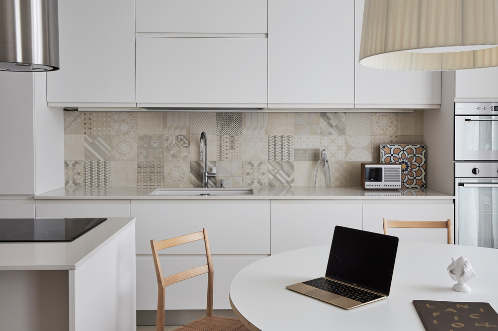 Mittelgroße Skandinavische Wohnküche mit flächenbündigen Schrankfronten, weißen Schränken, bunter Rückwand, Rückwand aus Mosaikfliesen, Küchengeräten aus Edelstahl und Kücheninsel in Mailand