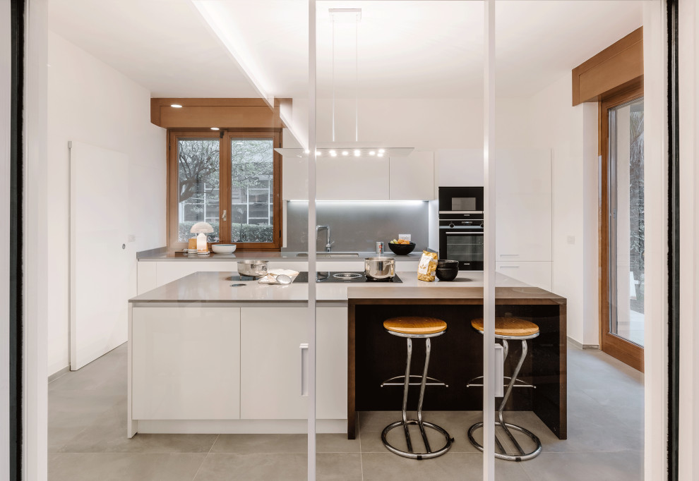 Cette photo montre une grande cuisine ouverte parallèle tendance avec un évier encastré, un placard à porte plane, un électroménager noir et îlot.